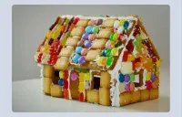 A photo of a gingerbread cookie house covered in colorful candies and white icing