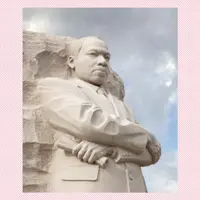 A close up photo of the MLK, Jr Memorial: A Tall statue of Dr. Martin Luther King, Jr carved out of granite standing with his arms crossed