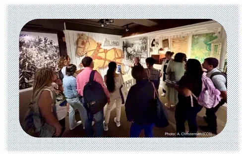 A group of people standing around a museum exhibit looking at items on the wall