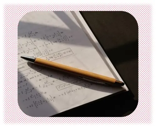 A pencil rests on a notebook containing handwritten mathematical equations