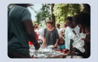 People stand in line to get food at a community barbecue.