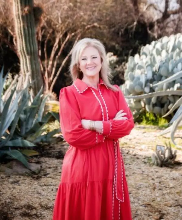 The
  woman
  is
  dressed
  in
  a
  red
  blazer,
  surrounded
  by
  various
  types
  of
  cacti
  and
  other
  desert
  plants.
  AI-generated
  content
  may
  be
  incorrect.